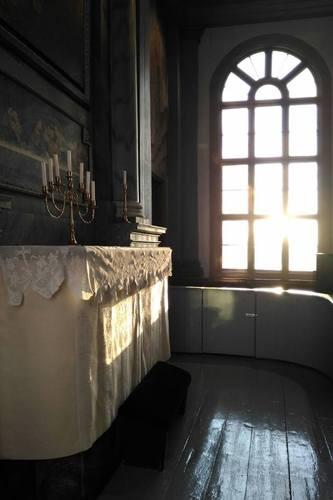 Solen lyser in i kyrkan på ett vittbeklätt altare