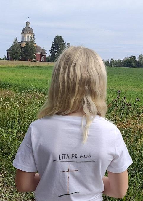 Flicka som ser ut över gräsfältet och Larsmo kyrka