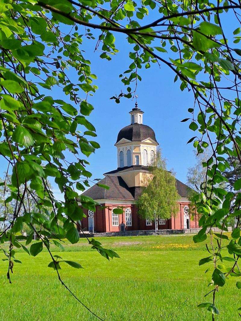 Larsmo skymtar bakom björkgrenar en solig sommardag.