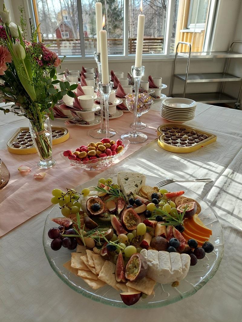 Frukt och ost fint upplagda på serveringsfat. Ljus i bakgrunden.